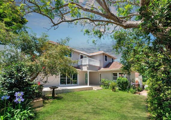 looking a renovated house through the garden trees from the backyard